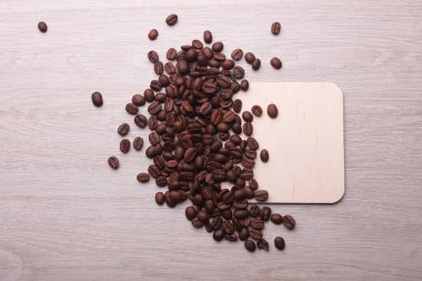 Ahşap kare, kahve çekirdekli bardak altlığı içer.