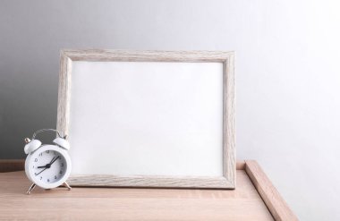 Gri zemin üzerinde saati olan beyaz boş fotoğraf çerçevesi