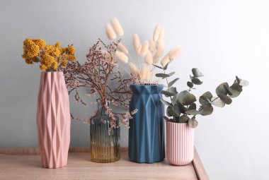 Ahşap masa üzerinde kuru çiçekli vazolar, gri arkaplan