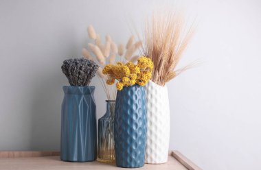 Masanın üzerinde kurumuş çiçekler olan vazolar.