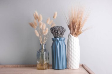Masanın üzerinde kurumuş çiçekler olan vazolar.