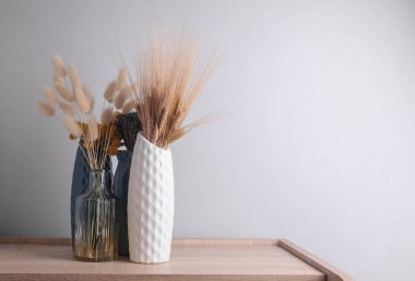 Masanın üzerinde kurumuş çiçekler olan vazolar.