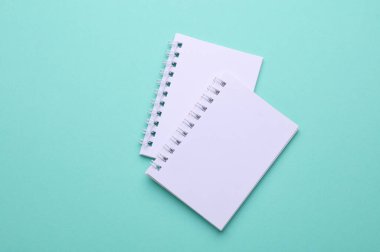 Naneli yeşil arkaplan üzerine Boş beyaz spiral not defterleri grubu