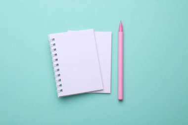 Nane yeşili arkaplanda kalem bulunan boş beyaz spiral defterler