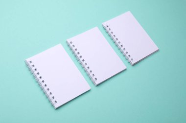 Naneli yeşil arkaplan üzerine Boş beyaz spiral not defterleri grubu