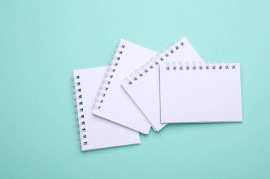 Naneli yeşil arkaplan üzerine Boş beyaz spiral not defterleri grubu