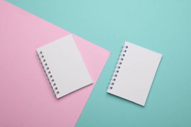 Pembe mavi arkaplan üzerine iki boş spiral defter.