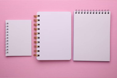 Pembe arkaplan üzerine beyaz boş spiral defter grubu