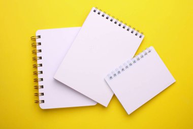 Sarı arkaplan üzerine beyaz boş spiral defter grubu