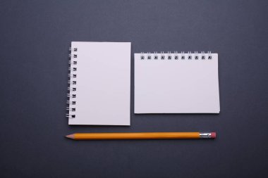 Koyu gri arkaplanlı beyaz, boş, sarmal defterler..