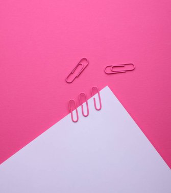 Pembe arka planda ataçları olan beyaz bir kağıt.