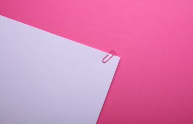 Pembe arka planda ataç olan beyaz kağıt.