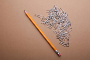 Kahverengi arkaplanda metal ataç ve kalem