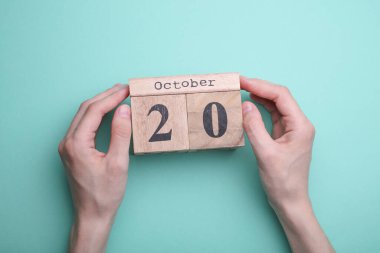 Elleri tahta blok takvimi ile 20 Ekim 'de nane yeşili zemin üzerinde