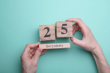 Elleri tahta blok takvimi ile 25 Ekim 'de nane yeşili zemin üzerinde