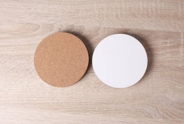 Ahşap arka planda içecekler için mantar ve beyaz bardak altlığı.