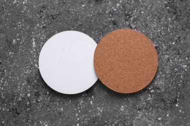 Beton arka planda içecekler için mantar ve beyaz bardak altlığı