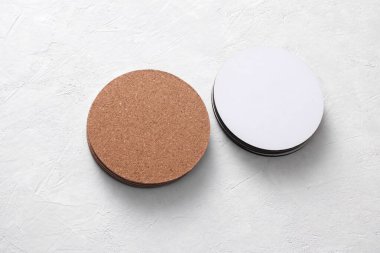 Beyaz beton arka planda içecekler için mantar ve beyaz bardak altlığı