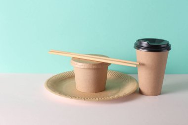 Karton paket servis kutuları ve nane yeşili arka planda tabaklar.