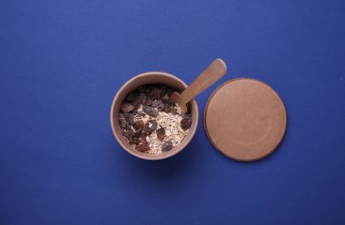 Üzümlü yulaf ezmesi, mavi arka planda tek kullanımlık el yapımı bir kutuda. Sağlıklı fast food