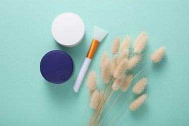 Nane yeşili arka planda lagurus çiçekleri olan gece ve gündüz krema kavanozları. Üst görünüm