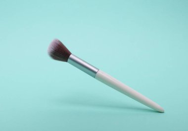 Nane yeşili arkaplanda yüzen makyaj fırçası