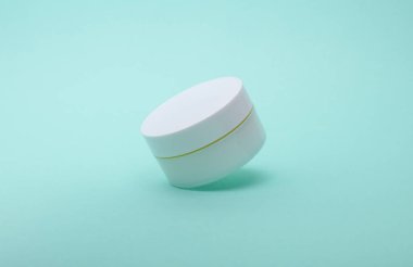 Nane yeşili zemin üzerinde yüzen beyaz krema kavanozu.