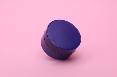 Pembe arka planda yüzen mavi krema kavanozu.