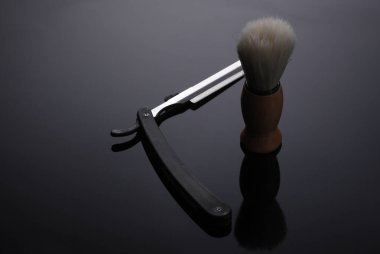 Tıraş fırçası düz bir jilet ile siyah bir arka planda yansıması ile