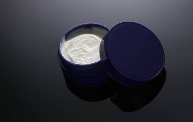 Siyah arka planda gece krema kavanozu.