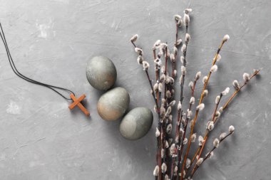 Easter eggs with Christian cross and pussy willow branches on grey concrete background. Top view