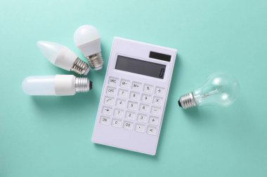 Nane yeşili arka planda ampulleri olan hesap makinesi. İş konsepti. Elektrik faturaları hesaplanıyor