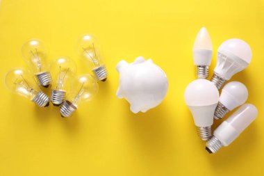 LED ve parlak ampuller ve sarı arka planda kumbara. Elektrik tasarrufu