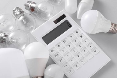 Gri arka planda hesap makinesi olan LED ve yeni çıkan ampuller. Elektrik tasarrufu