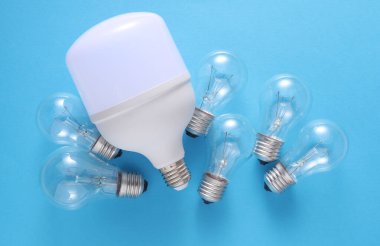 LED ve parlak ampuller mavi arkaplanda. Elektrik tasarrufu