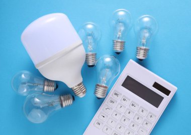 Mavi arka planda hesap makinesi olan LED ve yeni çıkan ampuller. Elektrik tasarrufu