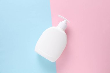 Mavi arkaplanlı beyaz sıvı sabun şişesi.