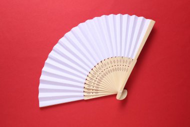 Kırmızı arka planda geleneksel beyaz Asya el vantilatörü.