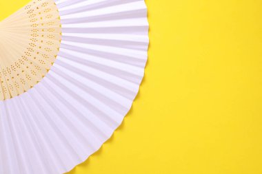 Sarı arka planda geleneksel beyaz Asyalı el vantilatörü. Boşluğu kopyala