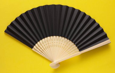 Sarı arka planda geleneksel Asyalı siyah el yelpazesi