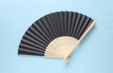 Mavi arka planda geleneksel siyah Asyalı el vantilatörü