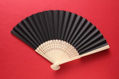 Kırmızı arka planda geleneksel siyah Asyalı el fanı