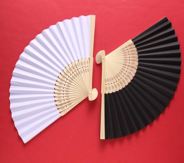 Kırmızı arka planda geleneksel siyah beyaz Asyalı el vantilatörleri