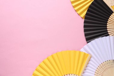 Pembe arka planda geleneksel Asyalı el hayranları.