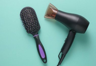 Modern siyah saç kurutma makinesi ve mavi arka planda saç fırçası.