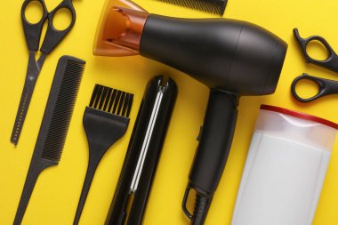 Sarı arka planda saç şekillendirme için düz saç modelleme aletleri ve aksesuarları vardı. Üst görünüm