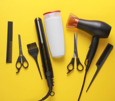 Sarı arka planda saç şekillendirme için düz saç modelleme aletleri ve aksesuarları vardı. Üst görünüm