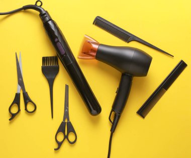 Sarı arka planda saç şekillendirme için düz saç modelleme aletleri ve aksesuarları vardı. Üst görünüm