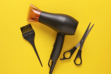 Sarı arka planda saç şekillendirme için düz saç modelleme aletleri ve aksesuarları vardı. Üst görünüm