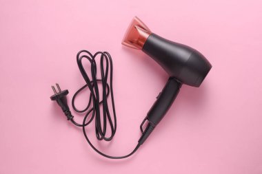 Pembe arka planda kablo ile siyah saç kurutma makinesi